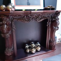 A wooden fireplace, richly decorated with ornaments.