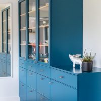 Blue chest of drawers, built-in cupboards at the bottom, glazed display cabinets at the top.