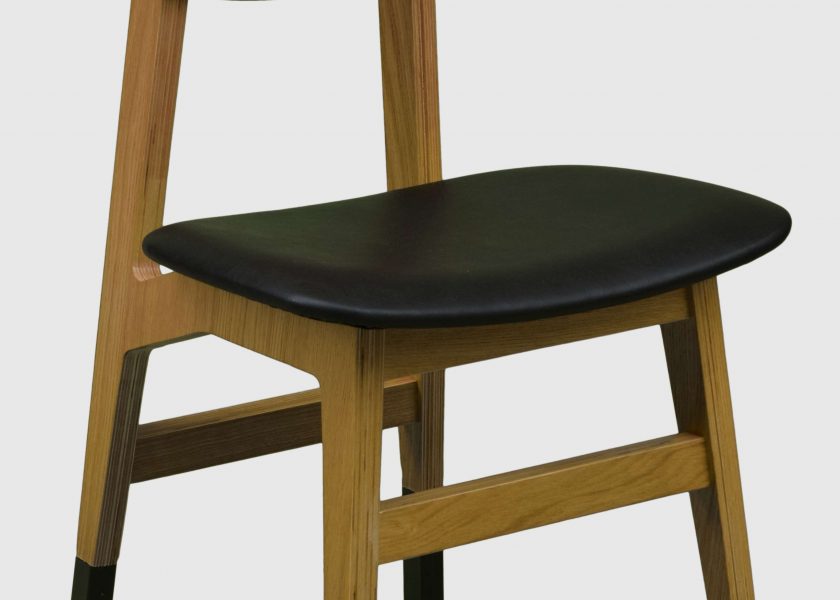 Zdjęcie przedstawia krzesło model LetoB z kolekcji firmy Jura. Krzesło posiada drewniane nogi oraz tapicerowane czarne siedzisko.