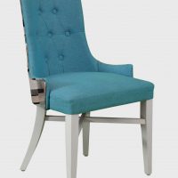 The picture shows the MaggieB model chair from the Jura collection. The chair has wooden legs and an upholstered blue seat.