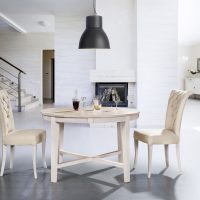 Inside the living room, a wooden table and two wooden chairs with light upholstery.